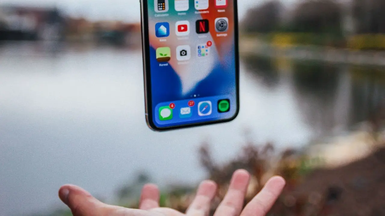 silver iPhone X floating over open palm